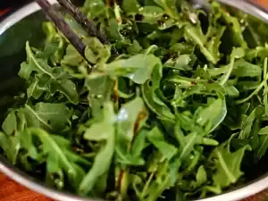 Tossing arugula in oil and balsamic glaze for Italian Cold Cut Sandwiches