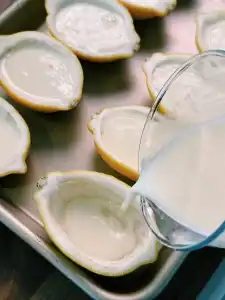 Pouring creamy custard into half lemon shells for Lemon Cream Custard