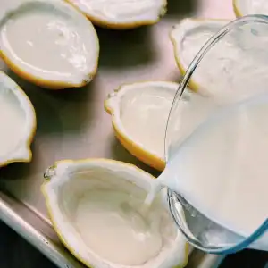 Pouring creamy custard into half lemon shells for Lemon Cream Custard