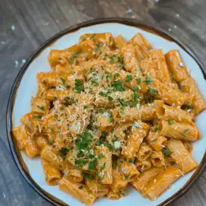 Top view of Chili Oil Vodka Pasta garnished with shredded Parmesan cheese and fresh parsley