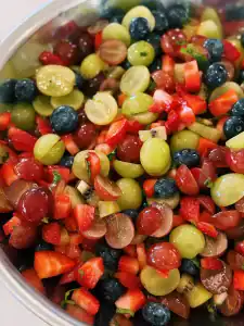 A bowl of fresh fruit salad with lemon honey fruit salad, with a mix of fruits like grapes, kiwi, and blueberry