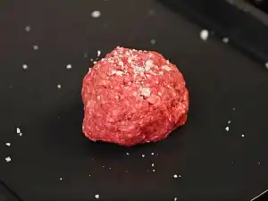A ball of ground beef seasoned with salad for Smash Burger