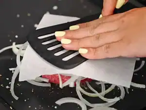 Pressing burger patties with a spatula and wax paper for smash burger