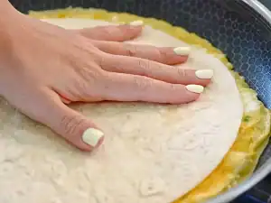 Lay the wrap on top of the frying egg to create the egg layer of the breakfast wrap