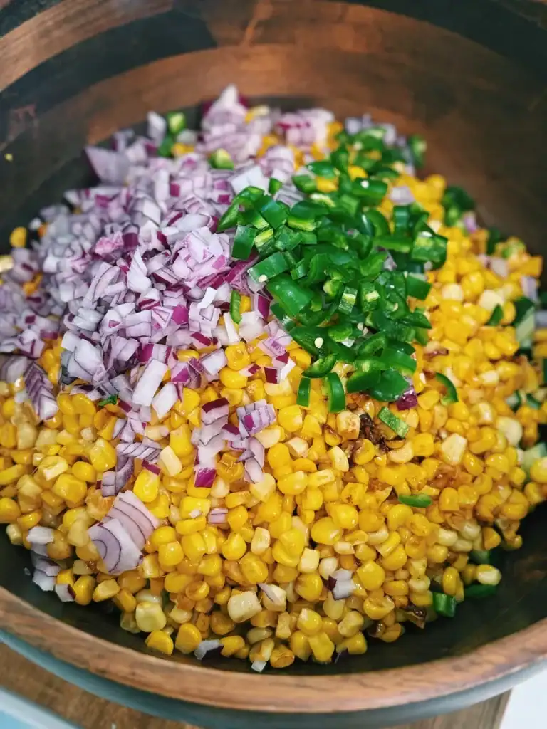 Chopped vegetables like cucumber, jalapeño, and red onion added to creamy corn chicken salad 