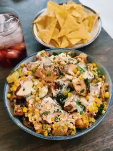 A bowl of creamy corn chicken salad served with tortilla chips