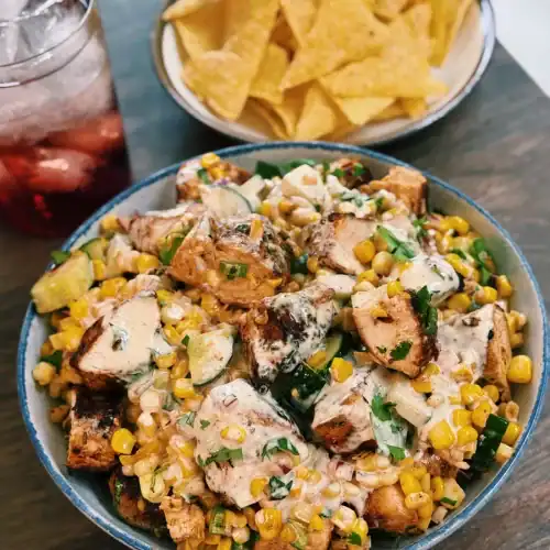 A bowl of creamy corn chicken salad served with tortilla chips