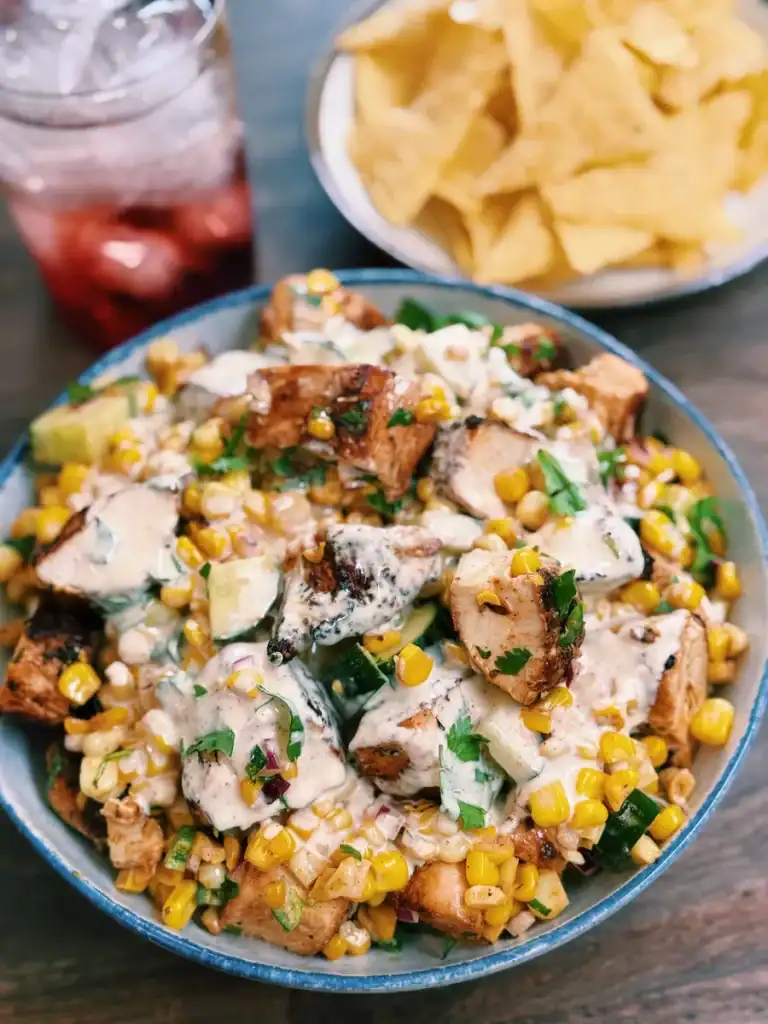A bowl of tex-mex inspired creamy corn chicken salad served with a bowl of tortilla chips