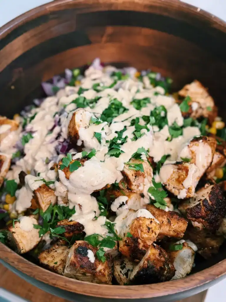 Adding dressing and garnish to Creamy Corn Chicken Salad before mixing