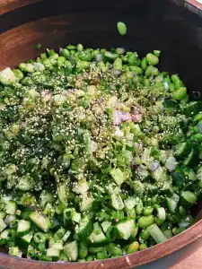 Fresh chopped green vegetables and sesame seeds in a wooden bowl for Edamame Chopped Salad