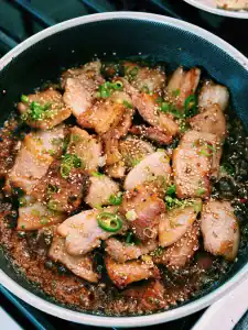 Korean Inspired Soy Glazed Pork Belly garnished with sesame seed and chopped green onion