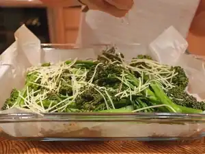 sprinkling shredded cheese and lemon juice on freshly roasted broccolini for Lemon Parmesan Broccolini