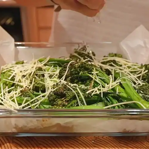 sprinkling shredded cheese and lemon juice on freshly roasted broccolini for Lemon Parmesan Broccolini