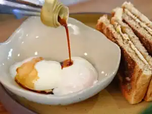 Adding Soy Sauce to half boiled eggs for Kaya Toast and Half Boiled Eggs