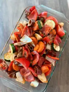 An oven dish full of freshly seasoned mixed vegetables for Roasted Veggie Soup.