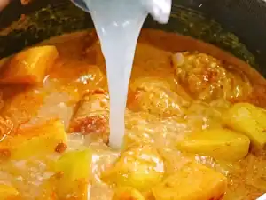 Rinsing out coconut cream can with water to add to Singaporean Chicken Curry