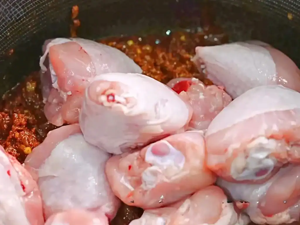 Adding chicken thighs to aromatic spice mix for Singaporean Coconut Chicken Curry