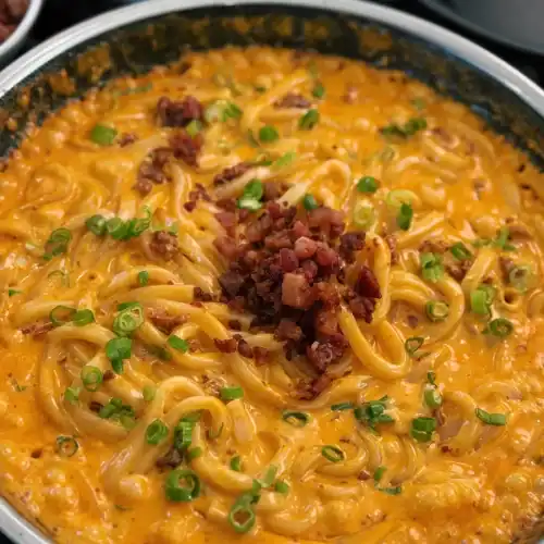 Topping the noodles with bacon bits for 10 Minute Spicy Creamy Bacon Udon