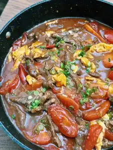 Adding sauce to tomato egg and beef stir fry