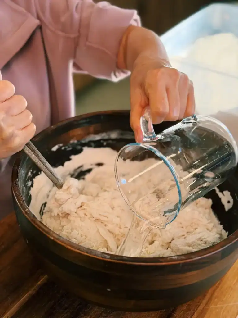 Making focaccia dough by mixing water and flour For scallion focaccia