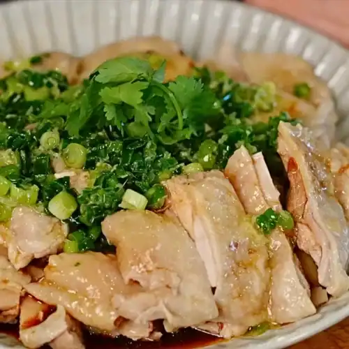 Scallion Ginger Poached Chicken topped with kai dong shallot scallion sauce, chopped cilantro, and ginger scallion oil