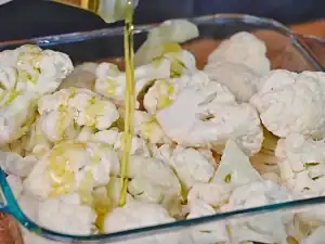 Add oil and seasonings to cauliflower for roasting the 1st time for Creamy Cheesy Cauliflower Bake