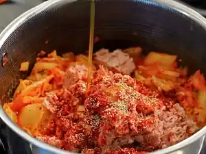 Adding dashi powder, sesame oil, and sugar to the pot for kimchi tuna stew