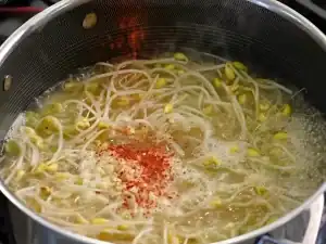 Adding gochugaru to simmering Korean Bean Sprout Soup