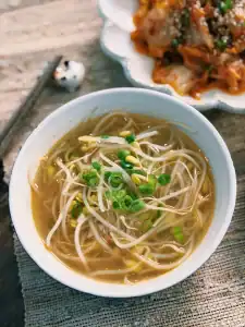 A bowl of Korean Bean Sprout soup garnished with chopped scallion