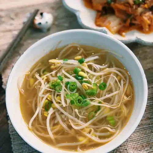 A bowl of Korean Bean Sprout soup garnished with chopped scallion