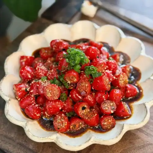 Sesame Yuzu Cherry Tomato Salad topped with chopped green onions.