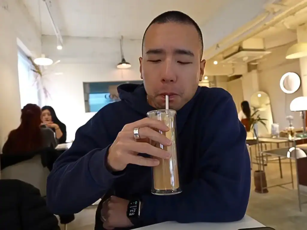 Dom Trying Concure Coffee’s Iced Latte, served in a tall thin glass.