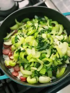 Adding cooked bok choy back into the pot of cooked rice with salted meat for Shanghaniese Cai Fan or Vegetable Rice with Salted Meat