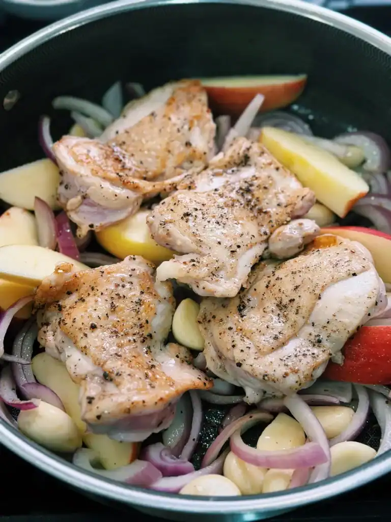 Adding pan-fried chicken back into the pan with apples, garlic, and red onions for Soy Glazed Apple Chicken