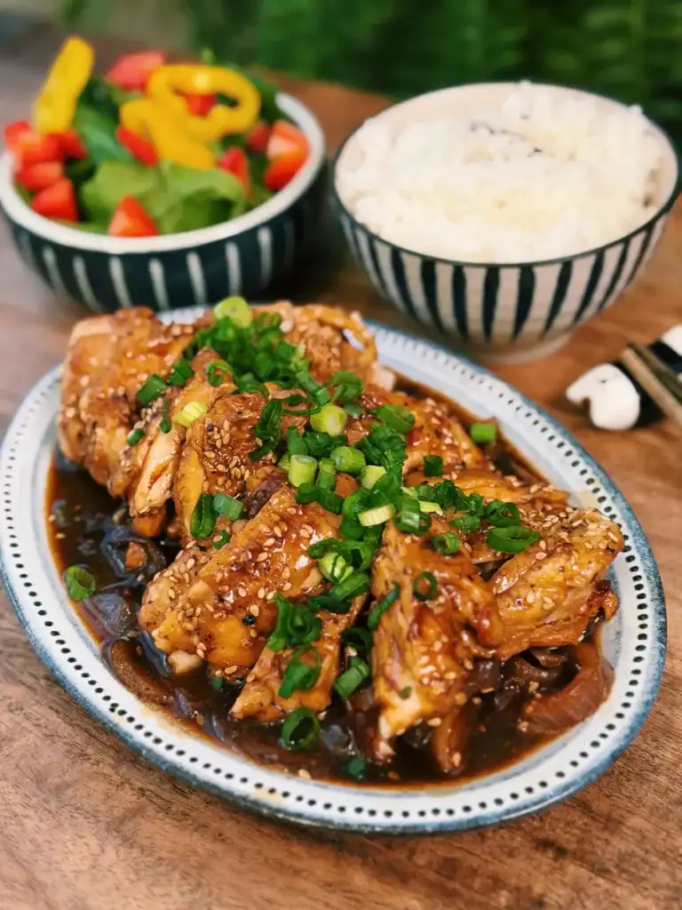 A plate of Soy Glazed Apple Chicken served with salad and rice