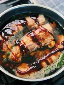 Adding seasoning and orange juice for simmeri Orange Glazed Pork Belly