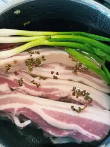 Blanching Pork Belly with Sichuan peppercorn and green onion stalks for Orange Glazed Pork Belly