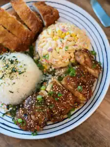Hawaiian Pineapple Shoyu Chicken sliced and shown as part of a Hawaiian Lunch Plate including macaroni salad rice, and chicken katsu