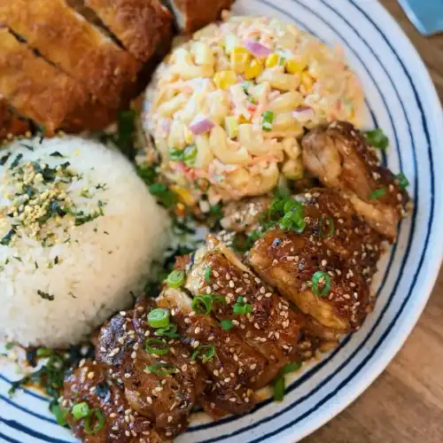 Hawaiian Pineapple Shoyu Chicken sliced and shown as part of a Hawaiian Lunch Plate including macaroni salad rice, and chicken katsu