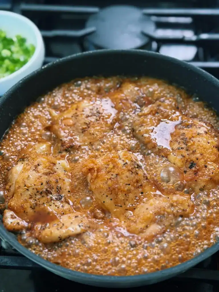 Simmering pan fried chicken thighs in Hawaiian Pineapple Shoyu Glaze for Shoyu Chicken