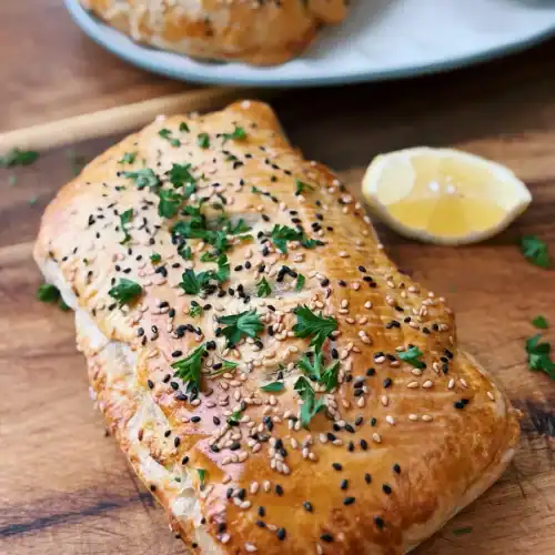 Crab Rangoon Hand pie garnished with lemon slice and chopped parsley