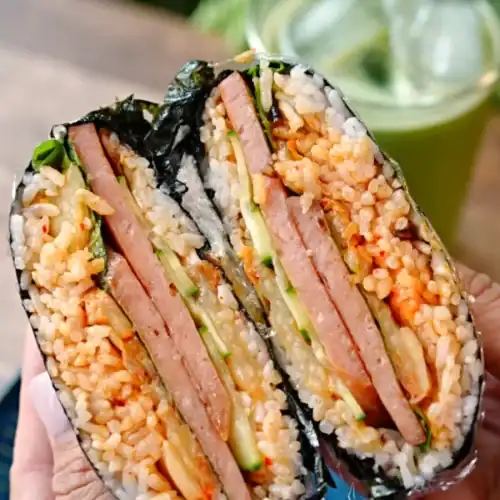 Cross section of a halved Spam Kimchi Onigirazu showing the layers of rice and fillings inside
