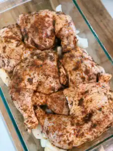 Seasoned chicken legs sitting on top of a bed of potatoes and onions for Oven Roasted Chicken Legs