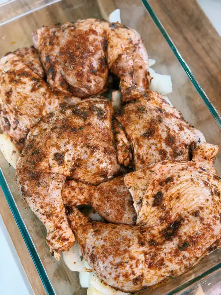 Seasoned chicken legs sitting on top of a bed of potatoes and onions for Oven Roasted Chicken Legs